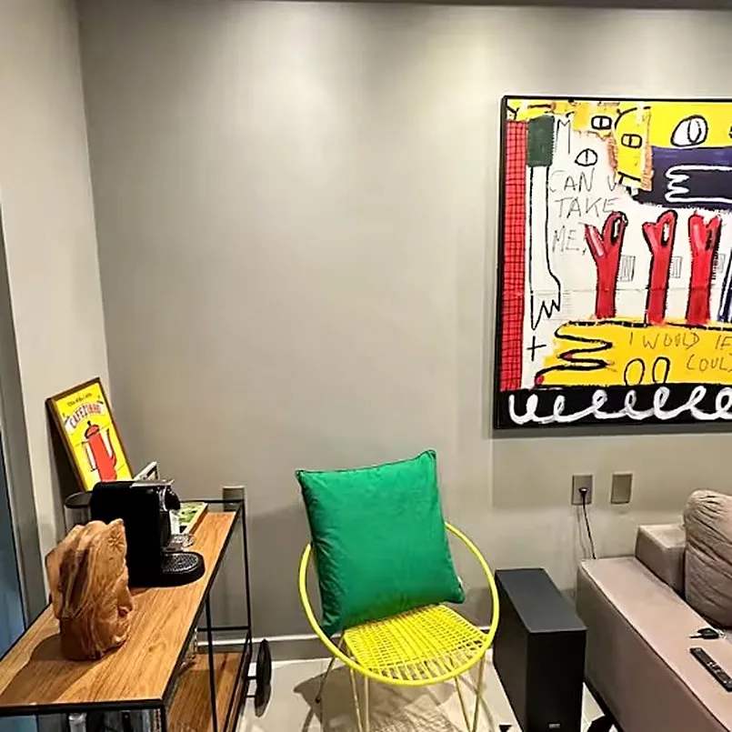 Cantinho do café com Nespresso, quadro colorido, almofada verde e cadeira amarela