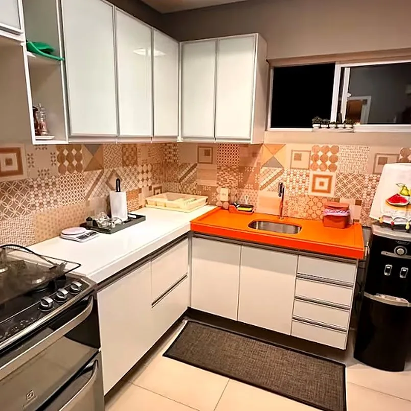 Cozinha com bancada laranja, azulejos estampados e fogão profissional